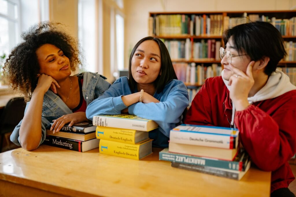 Tres estudiantes sentados alrededor de una mesa, estudiando con libros y apuntes. Representan el trabajo en equipo y la preparación académica para el examen ENAH 2026.