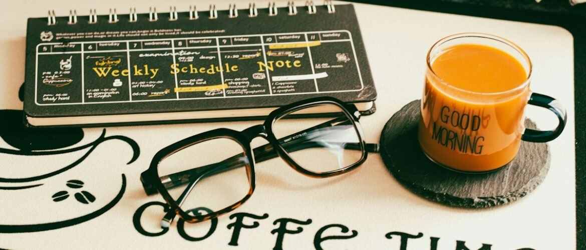 Planificador semanal junto a unos lentes y una taza sobre una mesa.